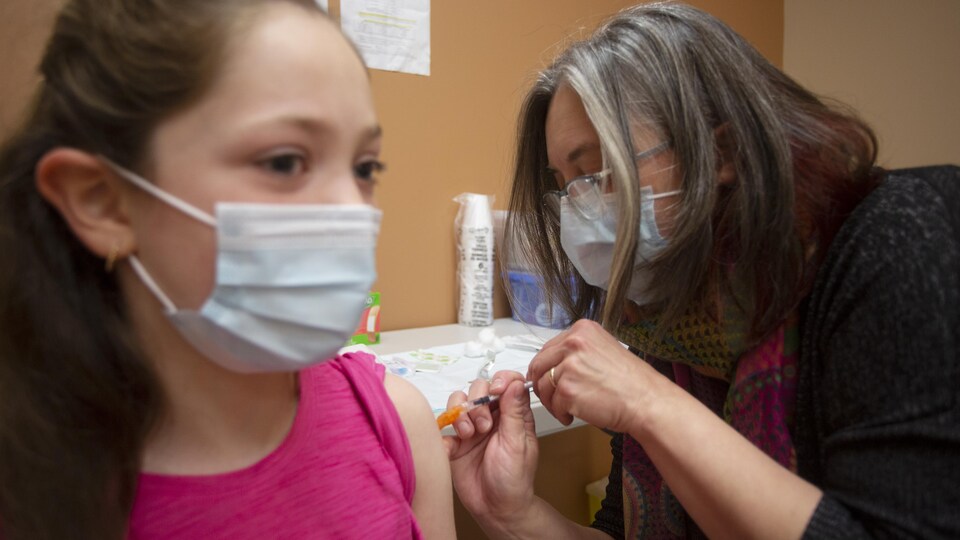 La médecin hygiéniste administre un vaccin à une jeune fille.