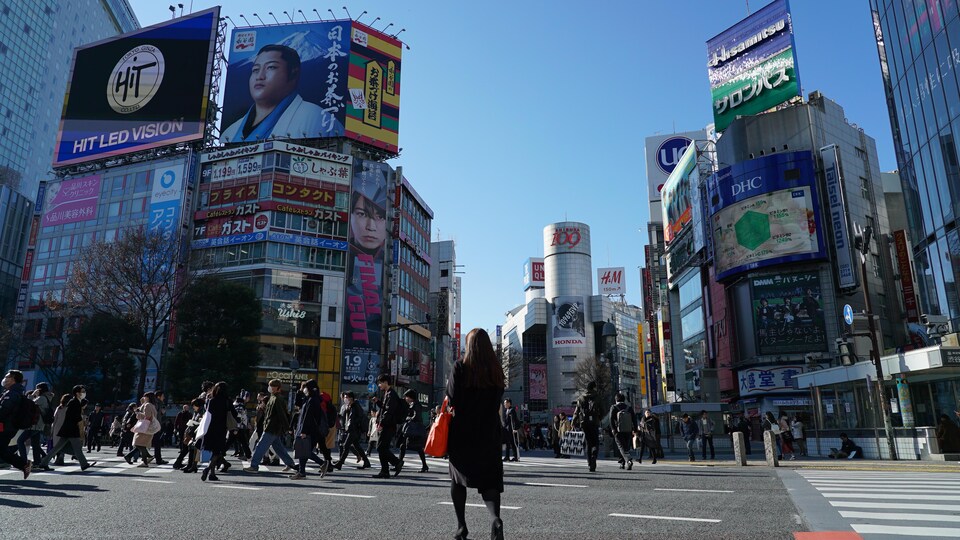 Une femme traverse le célèbre carrefour de Shibuya à Tokyo.