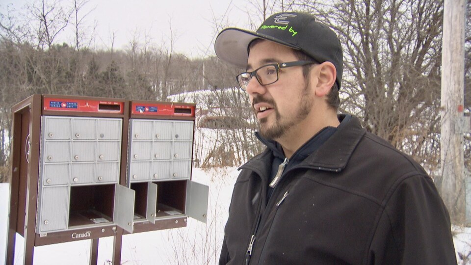 Jason Mougeot devant une boîte postale communautaire vandalisée de Postes Canada.