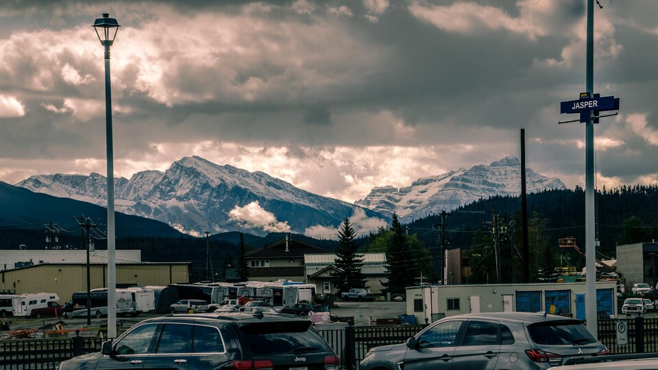 Des voitures sont stationnées à la gare de Jasper, dans la vallée de montagnes.