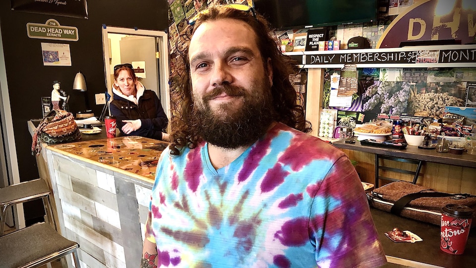 Un homme avec un t-shirt coloré sourit à la caméra
