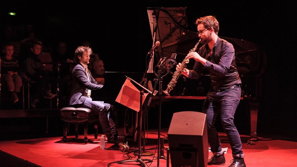 Un pianiste et un saxophoniste en spectacle devant un public