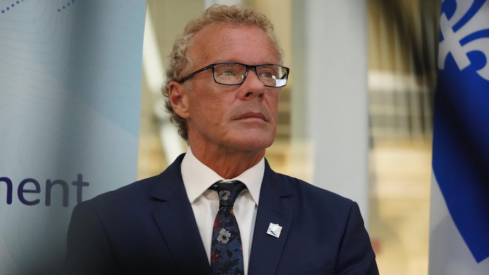 Le ministre Boulet debout, près d'un drapeau du Québec.