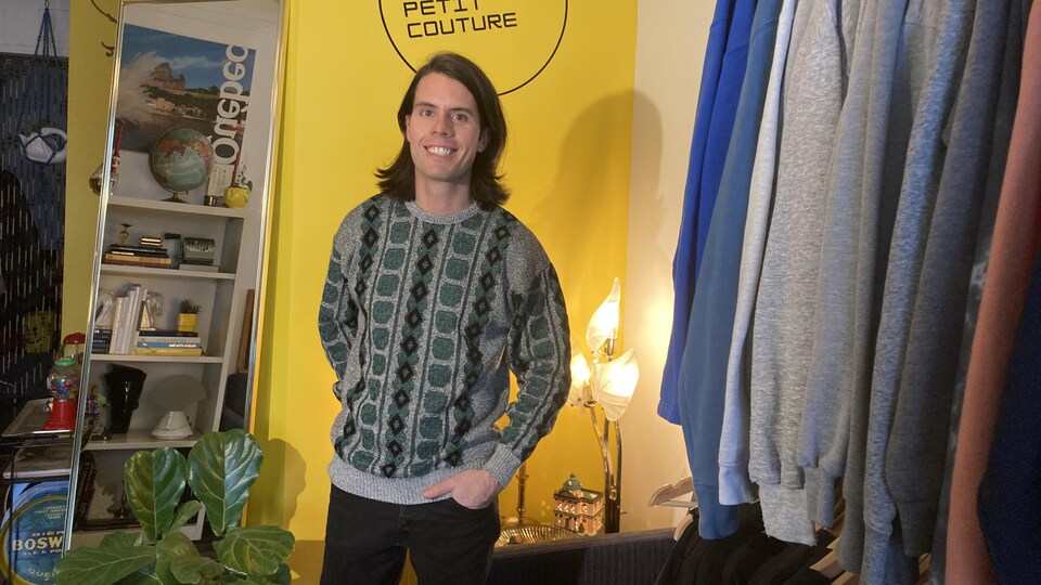 Un homme souriant dans une boutique de vêtements usagés.