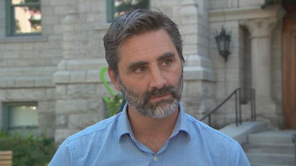 Un homme en entrevue face à la caméra devant l'hôtel de ville de Québec.