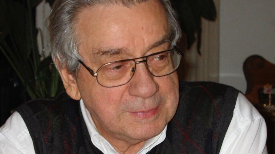 Portrait d'un homme âgé aux cheveux gris qui porte des lunettes.