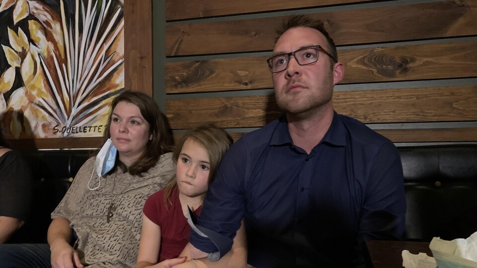 Jean-Marc Belzile assis avec sa fille et sa conjointe.