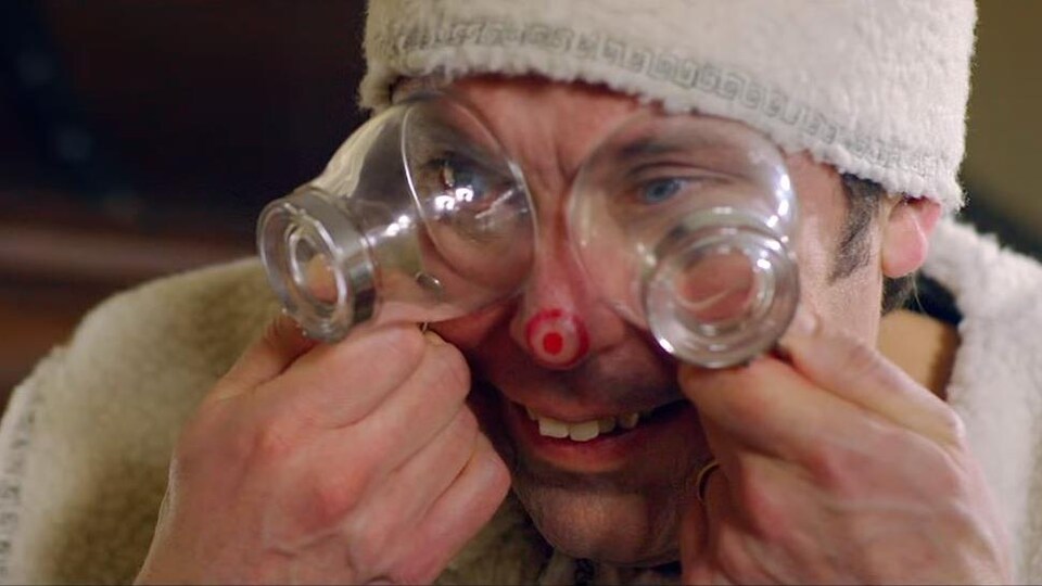 Un homme met deux verres sur ses yeux en souriant.