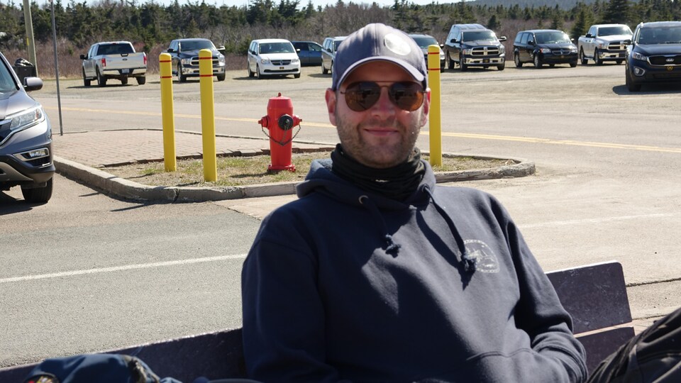 Jean-Martin Leblanc attend sur un banc à l'extérieur de l'aéroport des Îles-de-la-Madeleine à cause du retard du vol de Pascan. 