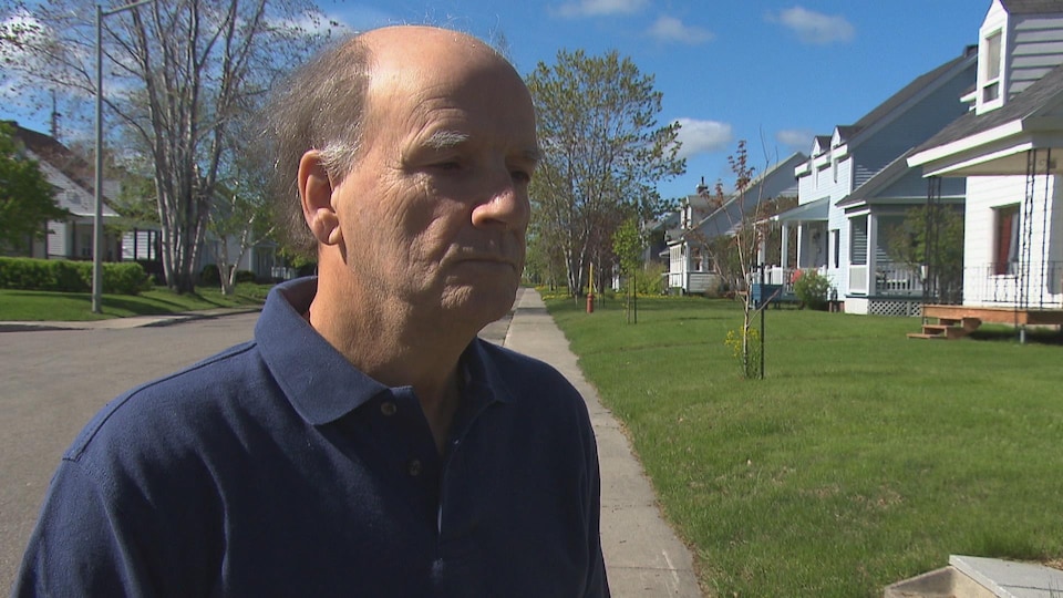 Un homme se tient devant une rangée de maisons.