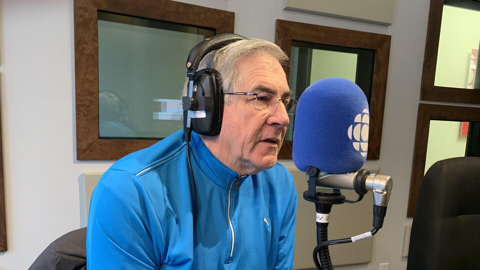 Un homme parle au micro dans un studio de Radio-Canada.