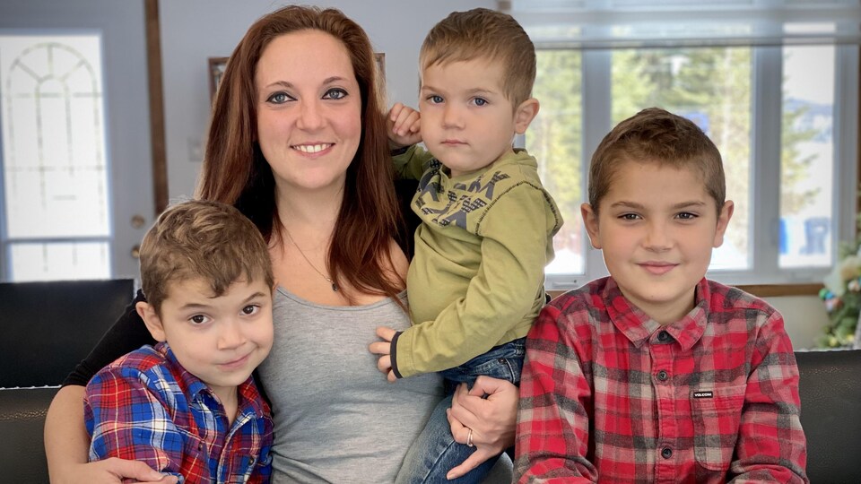 Une femme souriante accompagnée de trois enfants.