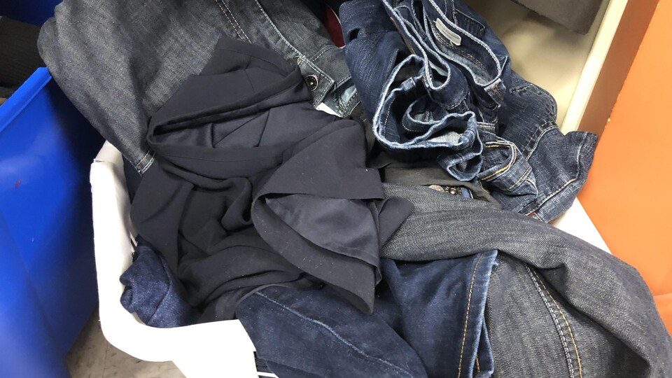 Des jeans empilés dans un bac.