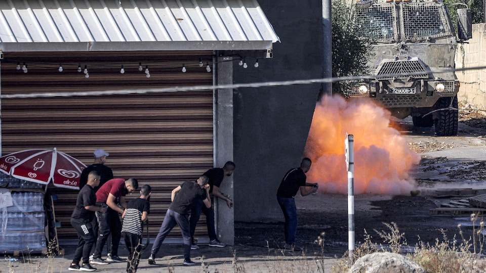 Une boule de feu près d'un véhicule militaire et des hommes derrière un mur
