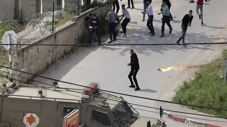 Young people throw Molotov cocktails at a military vehicle.