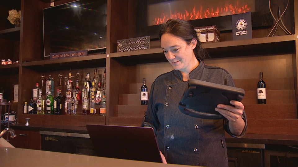 Une femme qui tient une tablette dans un restaurant. 