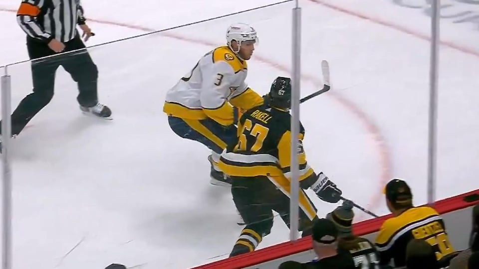 Jérémy Lauzon s'approche rapidement d'un joueur adverse près de la bande lors d'un match de hockey.