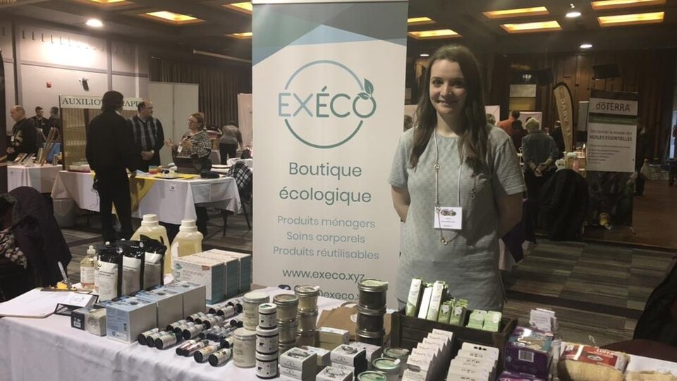 Jessie Vaillancourt et quelques-uns de ses produits ménagers et de soins corporels écologiques disposés sur une table.