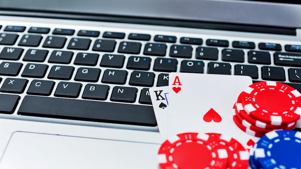 Des jetons de pokers et des cartes sont posés sur un clavier d'ordinateur. 