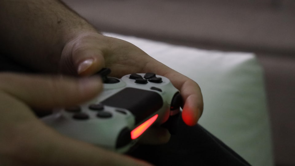 Des mains sur une console de jeu vidéo.