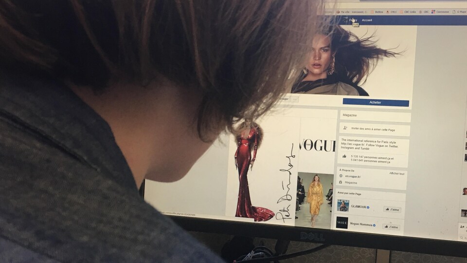 une jeune femme regarde la page du magazine Vogue sur Facebook