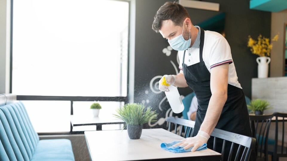 Un jeune serveur nettoie une table.