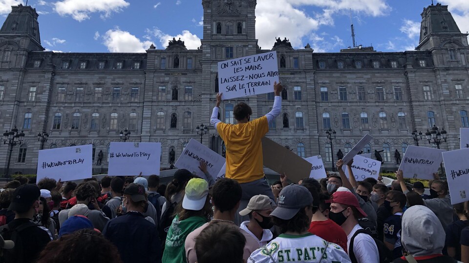 Des jeunes avec des affiches devant l'Assemblée nationale pour demander de pratiquer leurs sports.