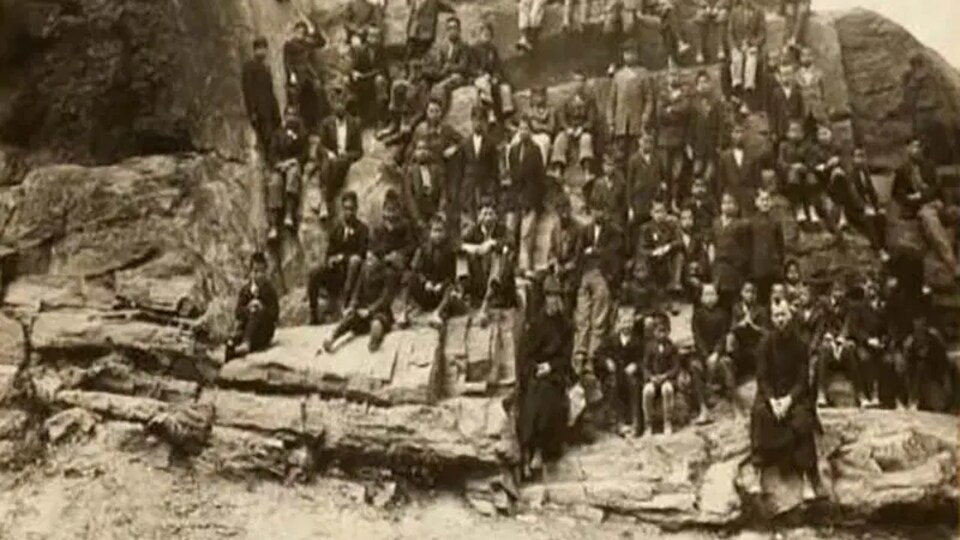 Une photo de groupes de jeunes assis autour d'une paroi rocheuse. 