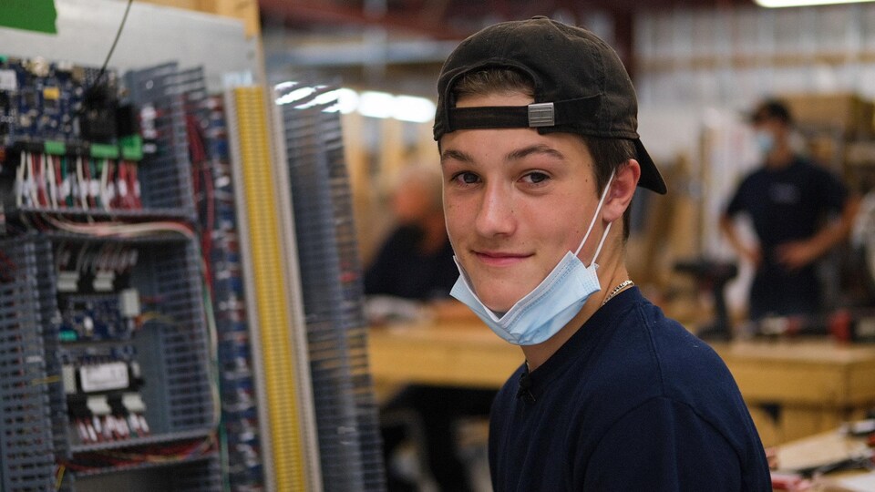 Un jeune homme sourit dans une usine.