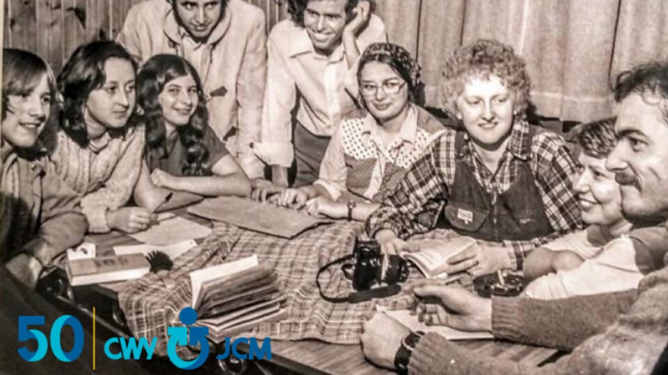 People sitting around a table in a black and white photo.