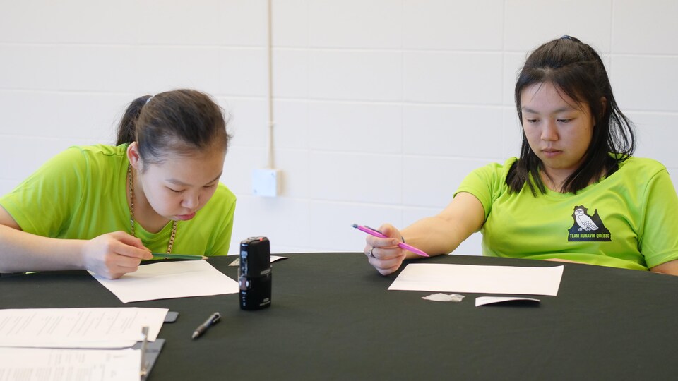 Deux jeunes personnes assises à une table, tenant un crayon dans les mains et faisant un dessin, le 1er février 2023, à Anzac, en Alberta.