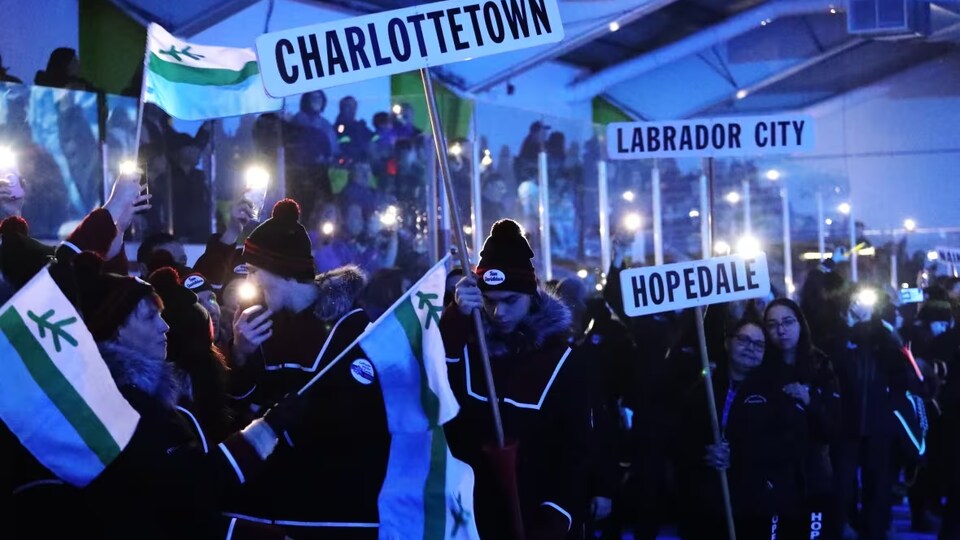 Des athlètes tenant des drapeaux et des affiches participent à la cérémonie d'ouverture des Jeux d'hiver du Labrador.