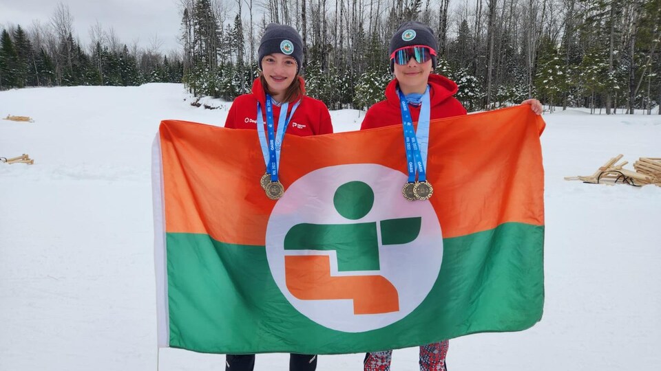 Deux jeunes athlètes prennent la pose, deux médailles d'or au cou chacun, en montrant le drapeau de l'Abitibi-Témiscamingue.