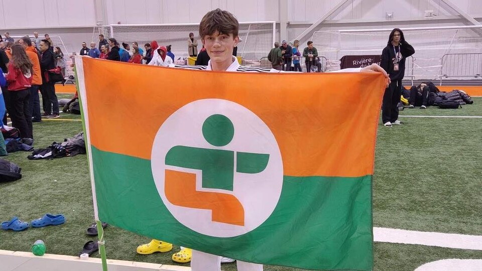 Thomas Warolin pose avec le drapeau de l'Abitibi-Témiscamingue.