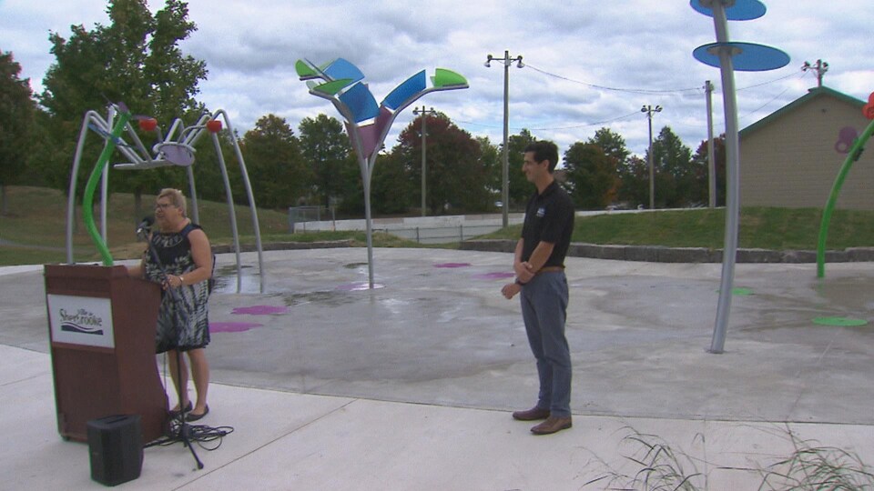 Deux personnes parlent devant des jeux d'eau.