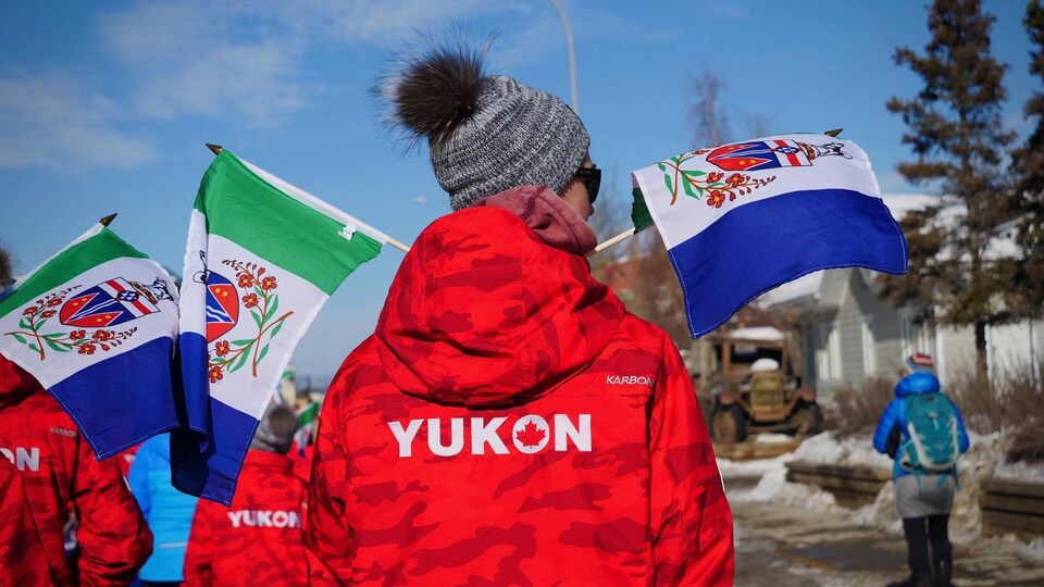 Un athlète porte un manteau aux  couleurs du Yukon lors d'une parade à Whitehorse en mars 2020.