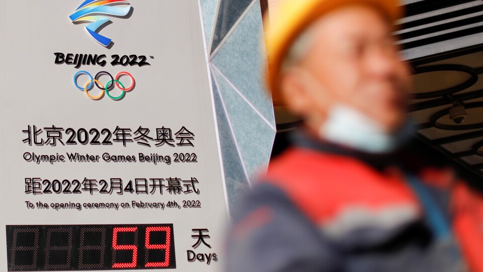 Un homme passe devant un compte à rebours numérique indiquant qu'il reste 59 jours avant le début des Jeux olympiques.