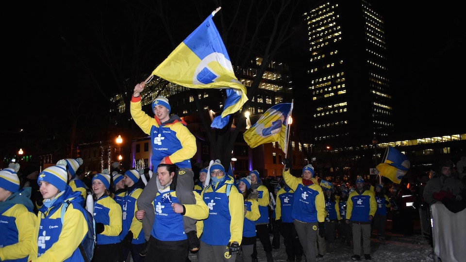 Des membres de la délégation de l'Est-du-Québec portent fièrement le drapeau qui les représente.