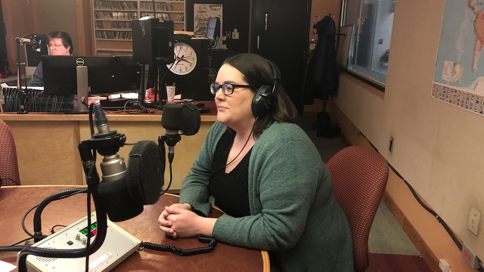 Jillian Kilfoil portant des écouteurs. Elle est assise et parle au microphone dans un studio radio. 