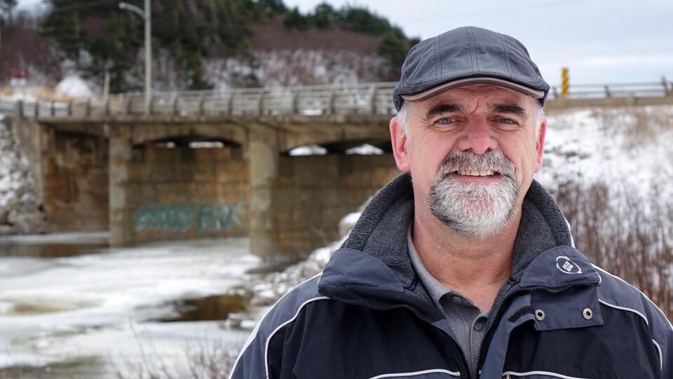 Jim Cashin se tient devant le pont de la rivière Romaine.