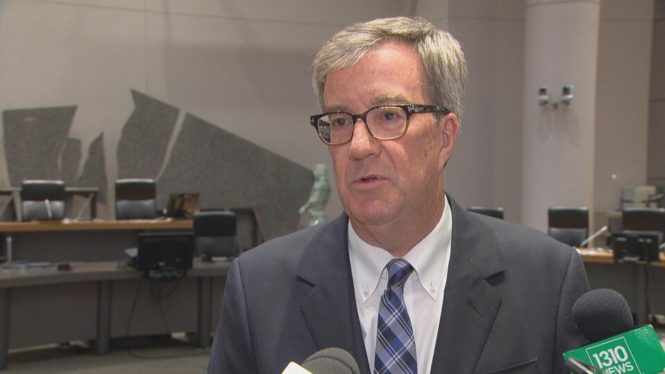 Jim Watson s'adresse aux journalistes dans la salle du conseil municipal.