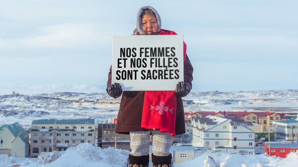 Une femme tient une affiche où l'on peut lire « Nos femmes et nos filles sont sacrées ».