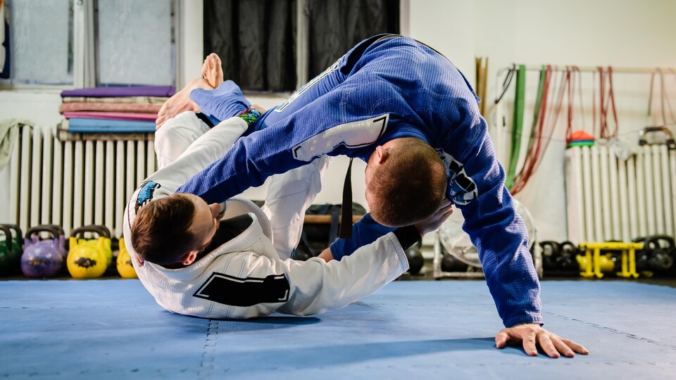 Deux athlètes pratiquant le jiu-jitsu brésilien dans un gymnase.