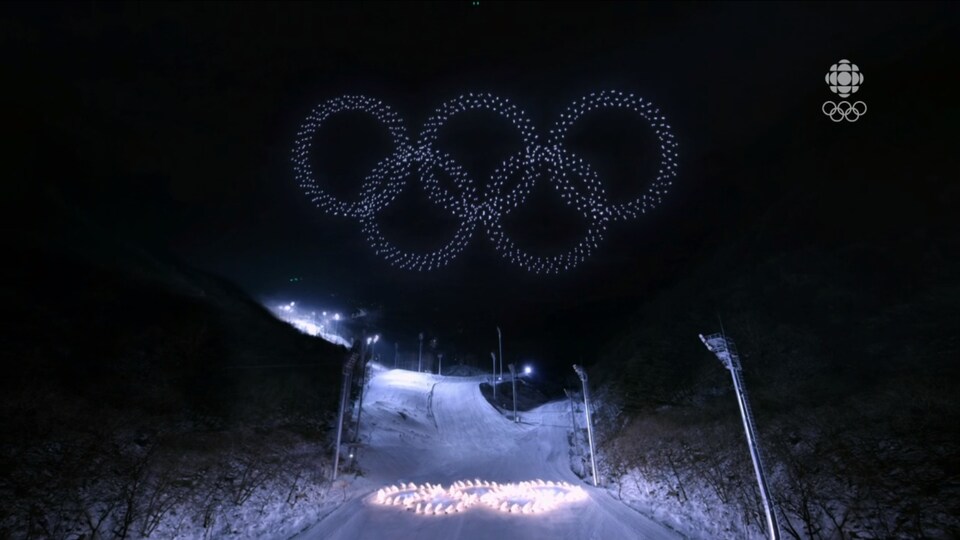 Plusieurs drones forment les anneaux olympiques flottant dans le ciel. 