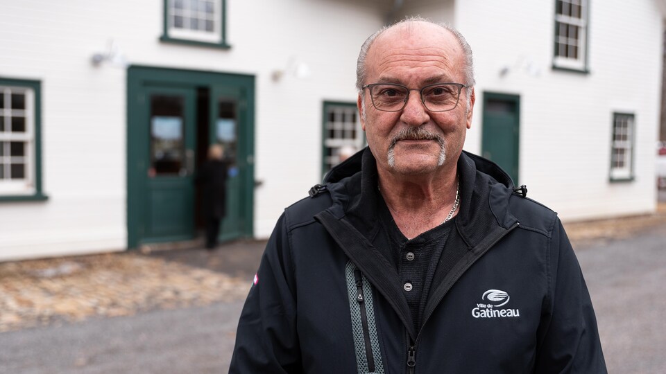 Un homme se laisse prendre en photo devant un bâtiment.