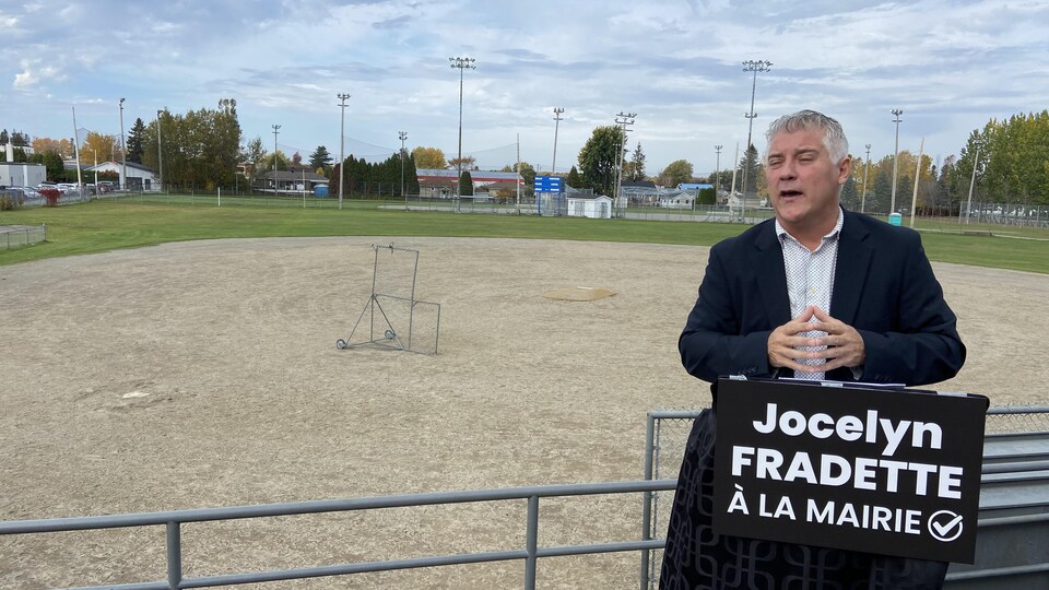 Le candidat à la mairie d'Alma Jocelyn Fradette devant le stade de baseball d'Alma.
