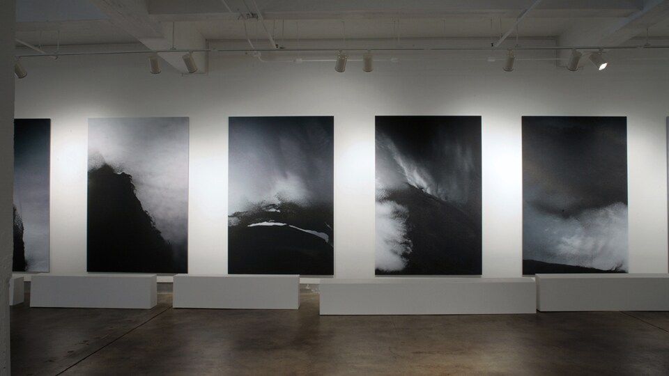 On voit quatre tableaux en noir et blanc dans une galerie.