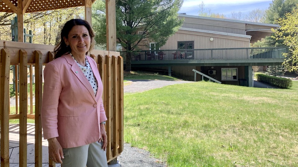 La dame accotée sur un gazebo en bois devant la bâtisse, située à Drummondville.