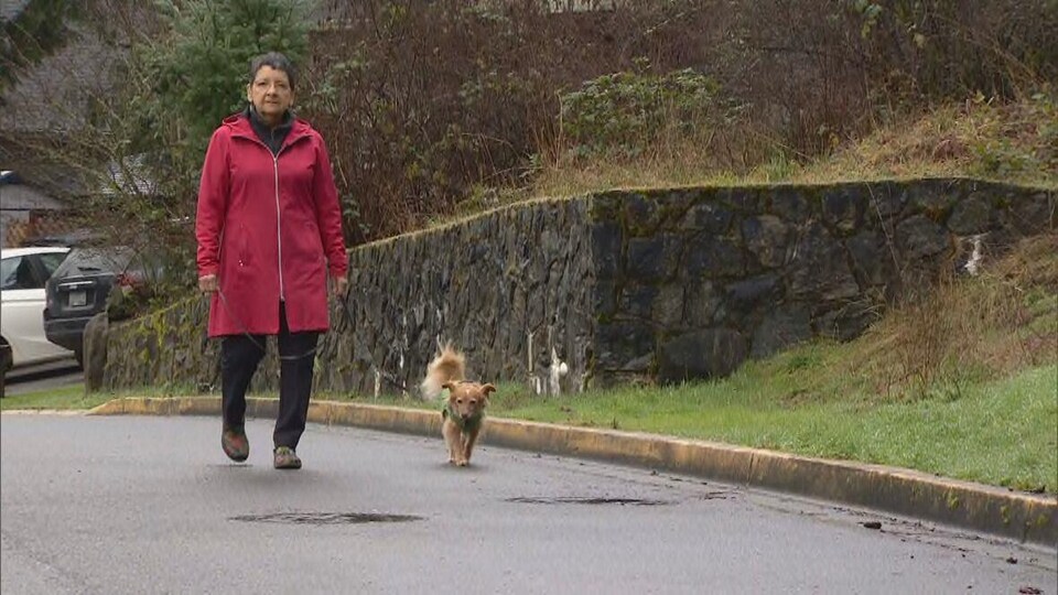 Une femme promène son petit chien.