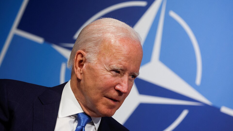 Gros plan de Biden devant un logo de l'OTAN.